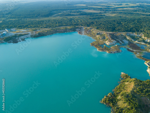 Drone view of an artificial lake of chalk quarries in Belarus near Krichev. Turquoise water in the summer season in an open pit. Man-made mountains formed during the extraction of chalk
