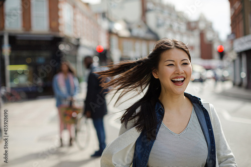 Smiling, enthusiastic young woman walking on sunny urban street