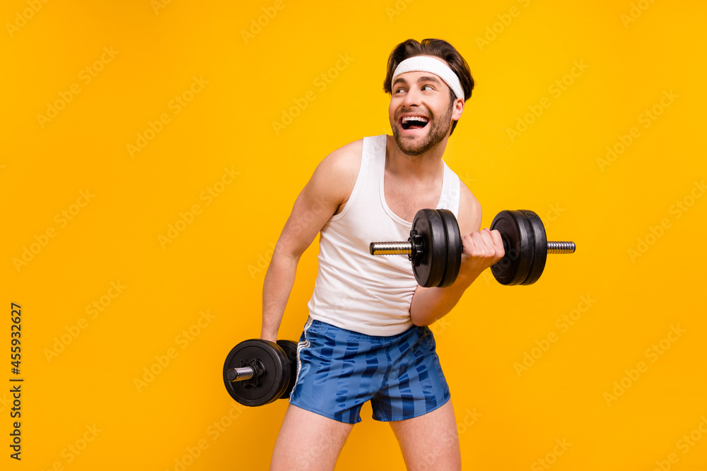 Obraz premium Portrait of attractive cheerful guy lifting weight working out active hobby isolated over bright yellow color background
