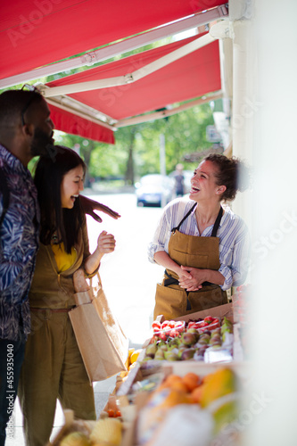 Canvastavla Female worker helping young couple shopping for fruit at market storefront
