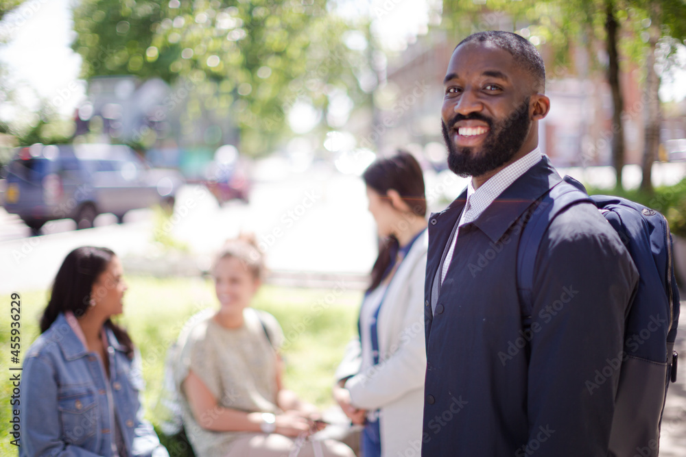 Portrait smiling businessman with backpack in urban park Portrait smiling businessman with backpack in urban park