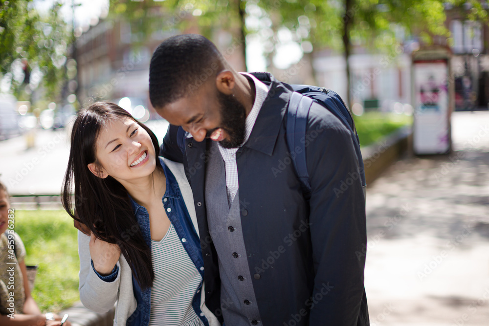 Portrait smiling, affectionate young couple hugging in sunny park Portrait smiling, affectionate young couple hugging in sunny park
