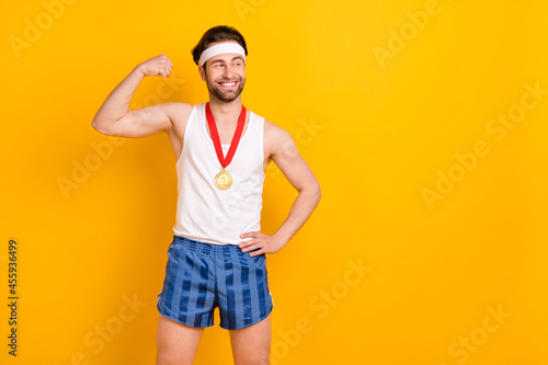 Portrait of attractive cheerful content guy leader demonstrating muscles copy space isolated over bright yellow color background