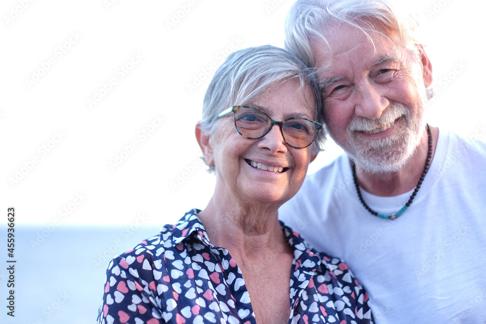 Portrait of beautiful senior couple smiling in outdoor at sea at sunset light. Caucasian couple white haired
