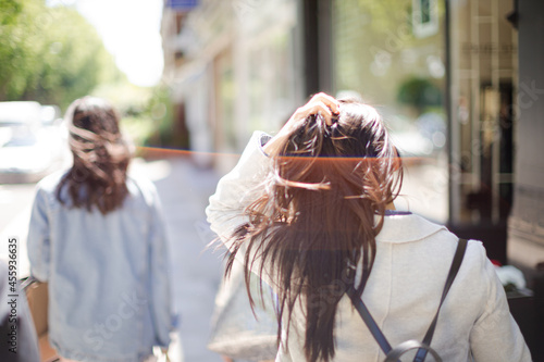 Young woman walking down urban street and playing with her hair © KOTO
