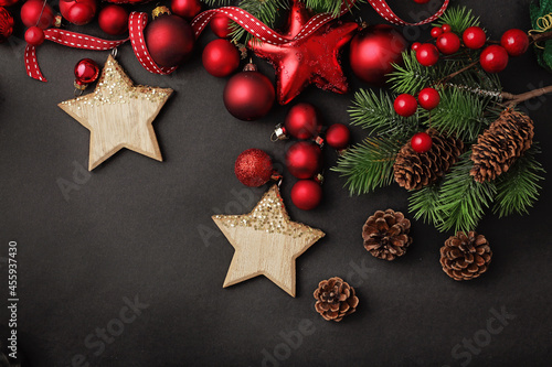 Christmas design on black background. christmas tree branches background. red ornaments, fir tree branches and pine cones