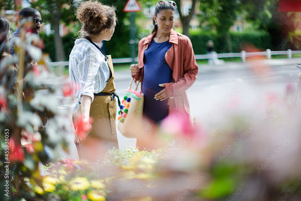 © KOTO - Female florist helping pregnant shopper at flower shop storefront