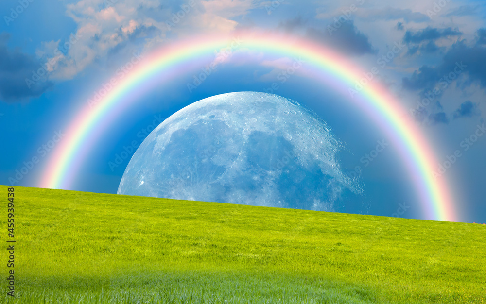 Beautiful landscape with green grass field, amazing rainbow over the moon in the background 