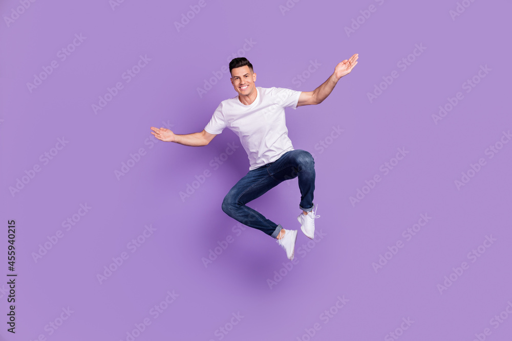 Full length photo of cheerful young happy man jump up funny funky mood active isolated on violet color background Full length photo of cheerful young happy man jump up funny funky mood active isolated on violet color background