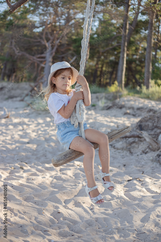 Naklejka premium Little girl on swings at the beach.