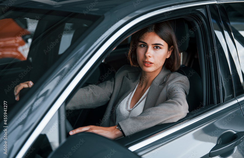 Woman testing new car. Sitting indoors in modern automobile