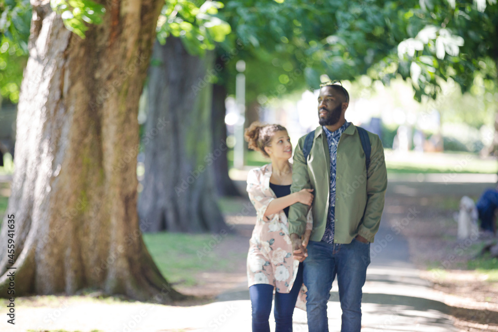 Fototapeta premium Young couple holding hands, walking in park
