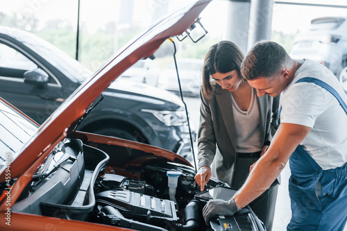 Showing results of work. Man repairing woman's automobile indoors. Professional service