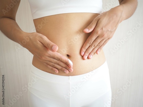 Weight loss and slim figure in a woman and she applied the cream on her belly skin. Excess fat or cellulite removal cream concept. closeup photo, blurred.