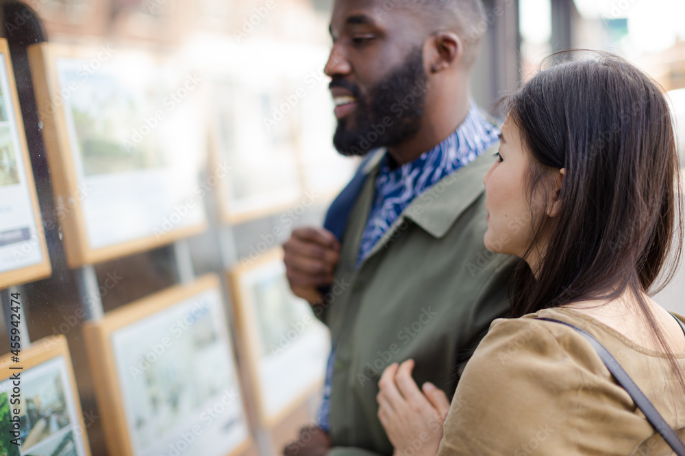 Young couple browsing real estate listings at storefront Young couple browsing real estate listings at storefront