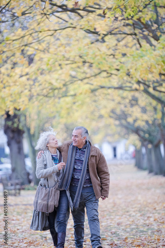 Affectionate couple hugging, walking among trees and leaves in autumn park © KOTO