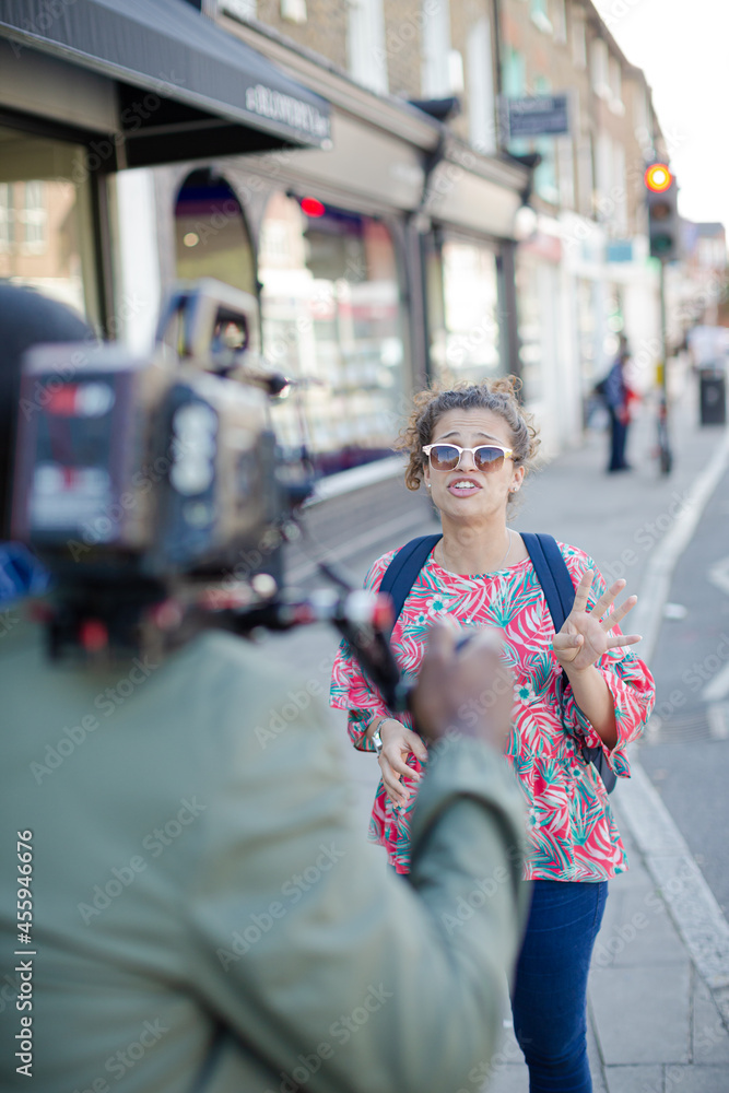 Enthusiastic young woman posing for video camera on urban street