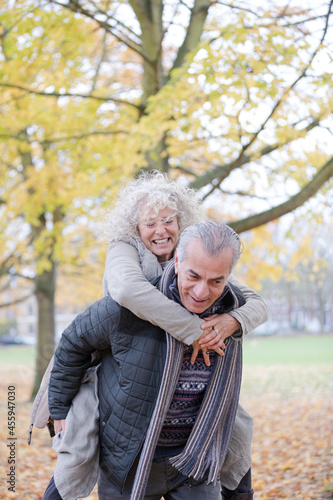 Senior man carrying woman on his back in autumn park