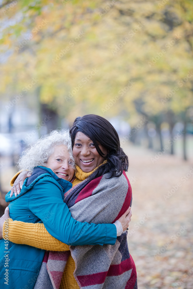 Fototapeta premium Enthusiastic senior women friends hugging in autumn park