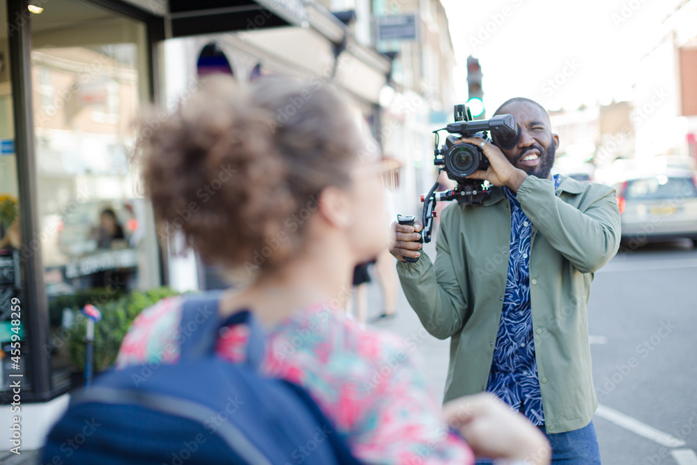 Young man with video camera videoing woman on street Young man with video camera videoing woman on street
