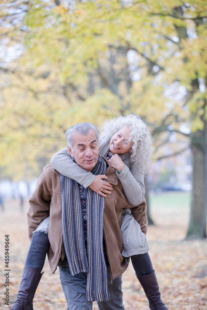 Senior man carrying woman on his back in autumn park Senior man carrying woman on his back in autumn park