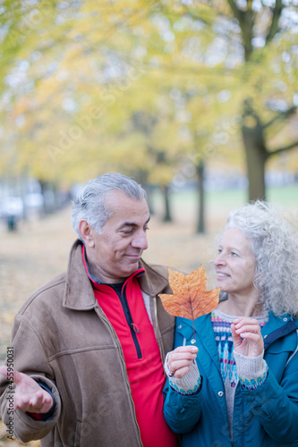 Affectionate senior couple holding orange autumn leaf