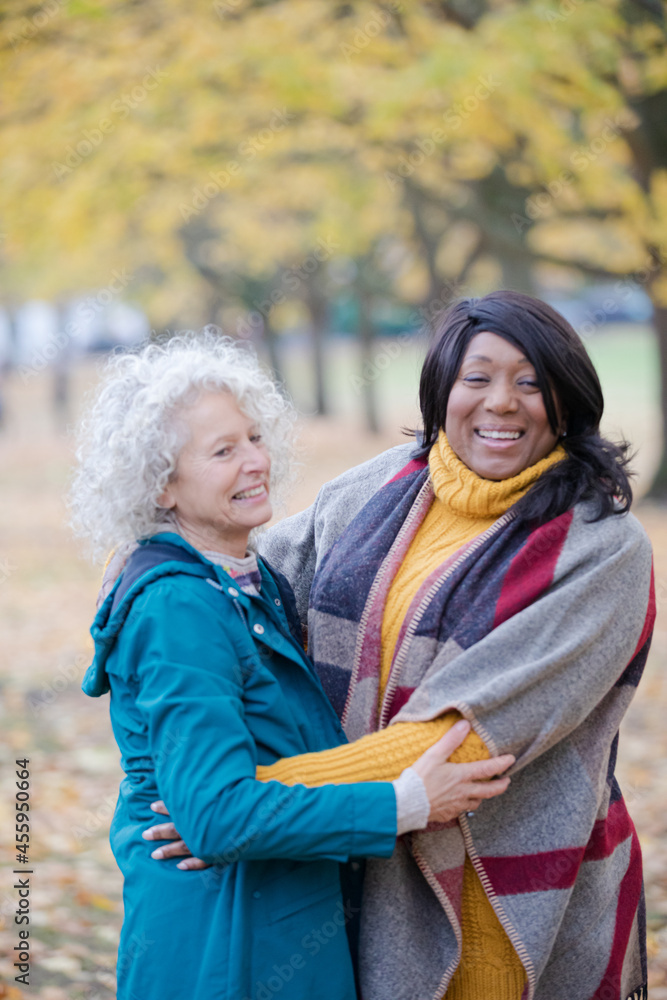 Fototapeta premium Enthusiastic senior women friends hugging in autumn park