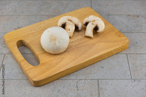 Large size champignon mushrooms placed on a wooden cutting board..