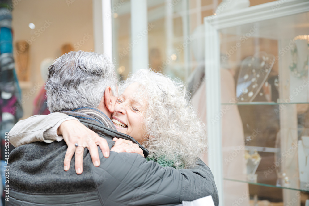 Senior couple hugging, window shopping at jewelry storefront Senior couple hugging, window shopping at jewelry storefront
