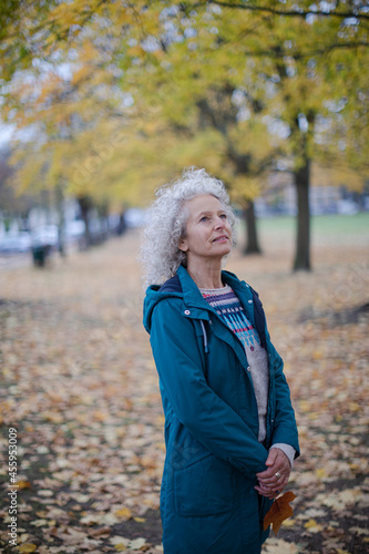 Senior woman standing amoung leaves in autumn park © KOTO