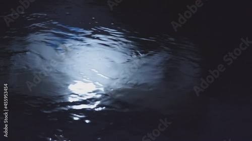 The stream of water that flows and reflects complex ripples in the gloom