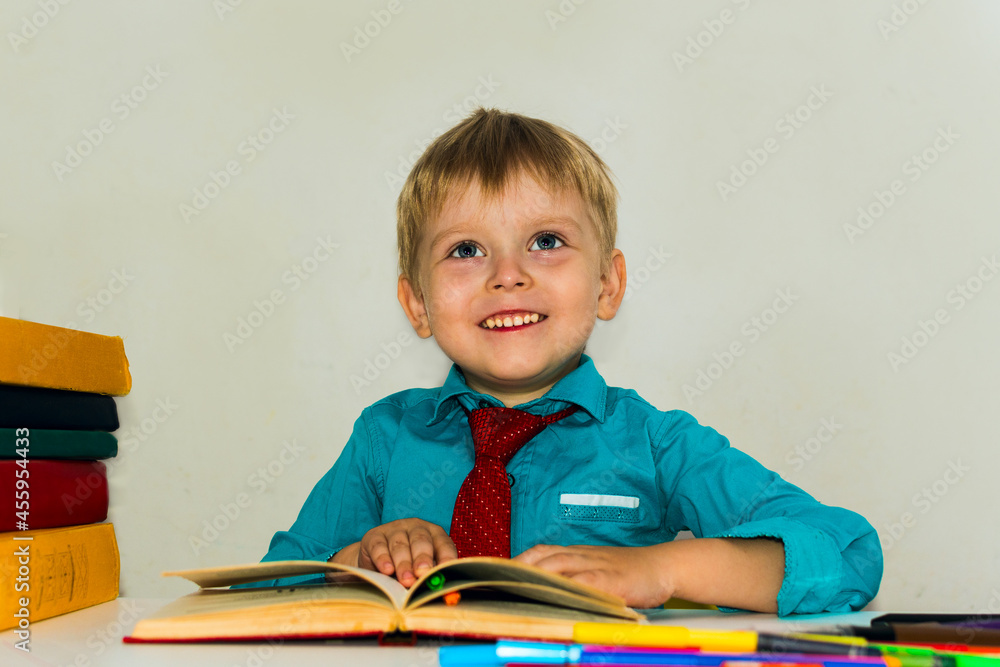smiling preschool boy at the table reading a book smiling preschool boy at the table reading a book