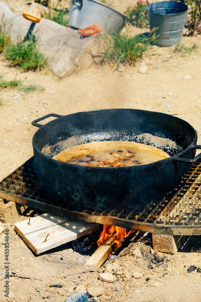 Pork frying in black cooking pot at farm during sunny day Pork frying in black cooking pot at farm during sunny day