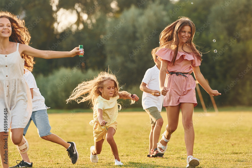 Fototapeta premium Beautiful sunlight. Group of happy kids is outdoors on the sportive field at daytime