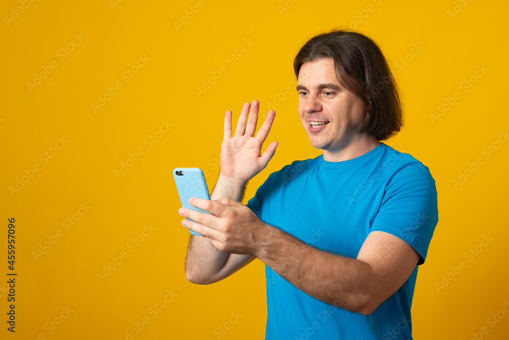 Handsome man doing video call waving to smartphone winking looking at the camera, cheerful and happy face. Handsome man doing video call waving to smartphone winking looking at the camera, cheerful and happy face.