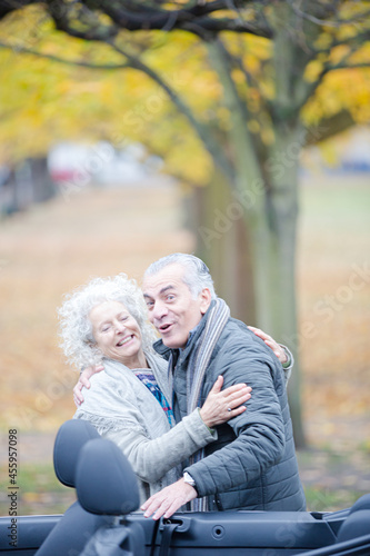 Affectionate, tender senior couple hugging in autumn park near car