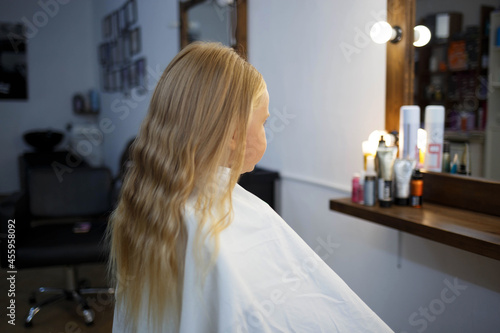hairdresser straightens hair of a little girl in a beauty salon