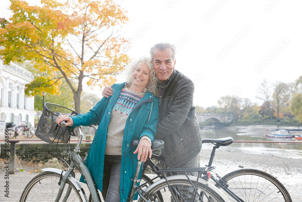 Obraz premium Portrait smiling senior couple bike riding along autumn river