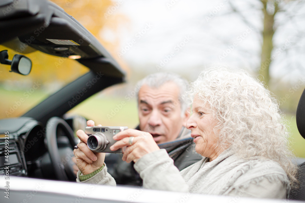 Active senior couple using digital camera in car Active senior couple using digital camera in car