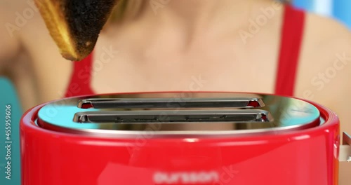 The girl takes out burnt bread from the toaster. 