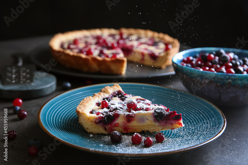 Sprinkling powdered sugar onto piece of delicious currant pie on grey table, closeup © New Africa