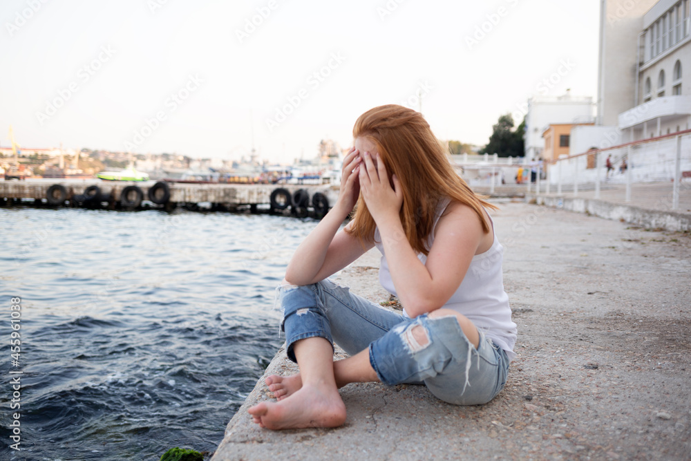 a teenage girl sits on the seashore. the concept of problematic adolescents, depressive states a teenage girl sits on the seashore. the concept of problematic adolescents, depressive states