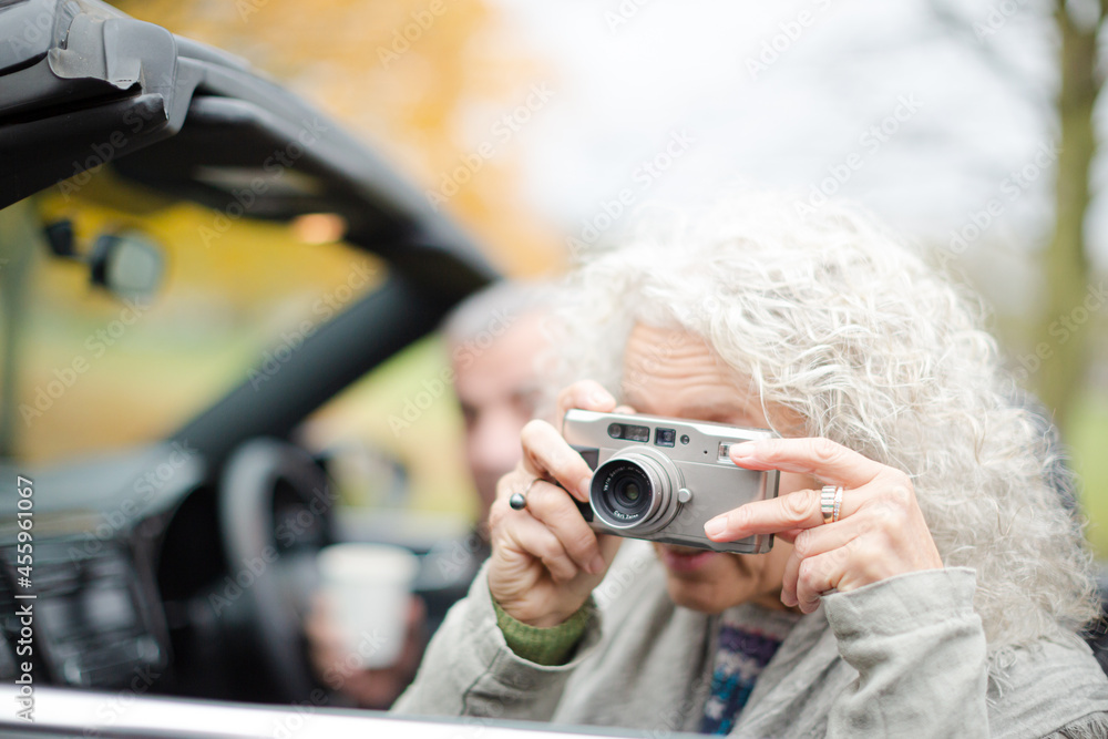 Naklejka premium Active senior couple using digital camera in car
