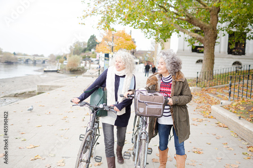 Wallpaper Mural Smiling active senior women walking bicycles in autumn park Torontodigital.ca