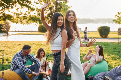 Women posing for the camera. Group of young people have a party in the park at summer daytime