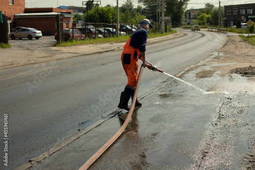 A worker washes the road with a hydrant.