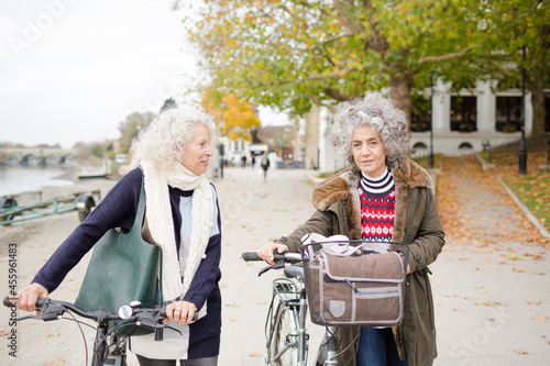 Smiling active senior women walking bicycles in autumn park © KOTO