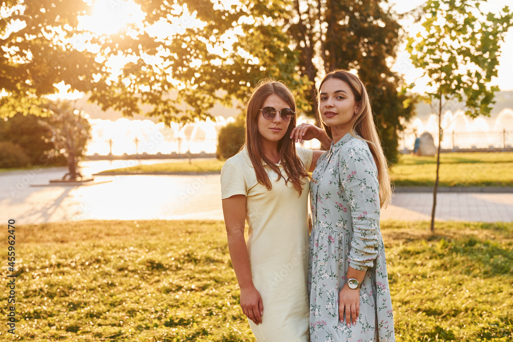 Fototapeta premium Two women standing in the autumn park together. Beautiful sunshine
