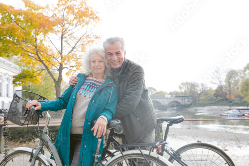 Portrait smiling senior couple bike riding along autumn river