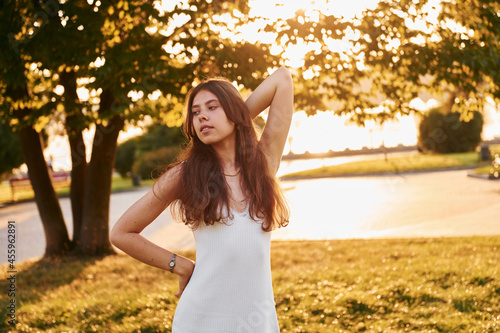 Posing for a camera. Woman standing in the autumn park. Beautiful sunshine